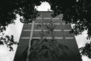 Photo of a stencil art mural with hands scratching the facade of 9 story building by futuro berg